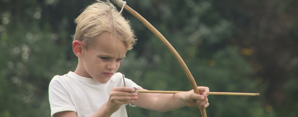 A young boy tries his hand with a bow and arrow.
