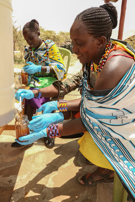 Glass bottles are filled with honey by Maasai ladies