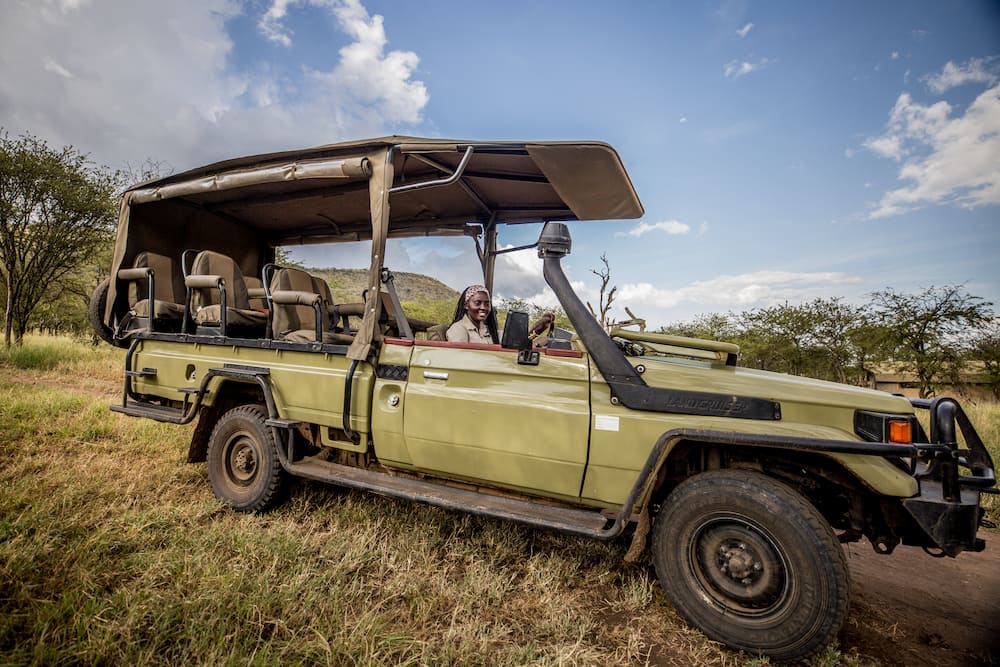 Zawadi, one of Dunia Camp’s female safari guides, is all smiles in her safari vehicle.