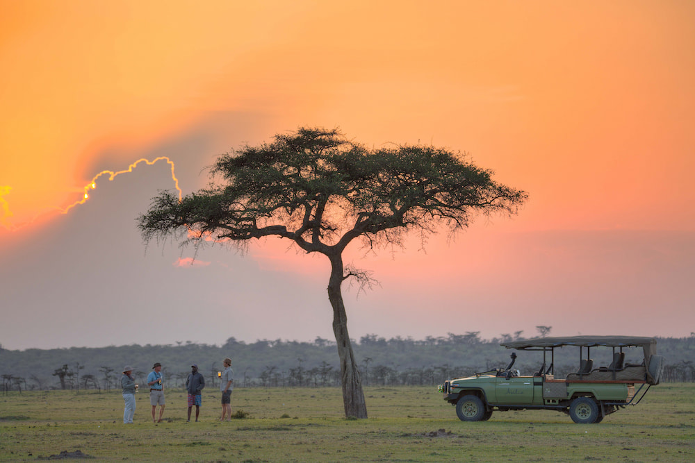Guests enjoying a drink at sunset on the plains of the Mara Naboisho Conservancy.