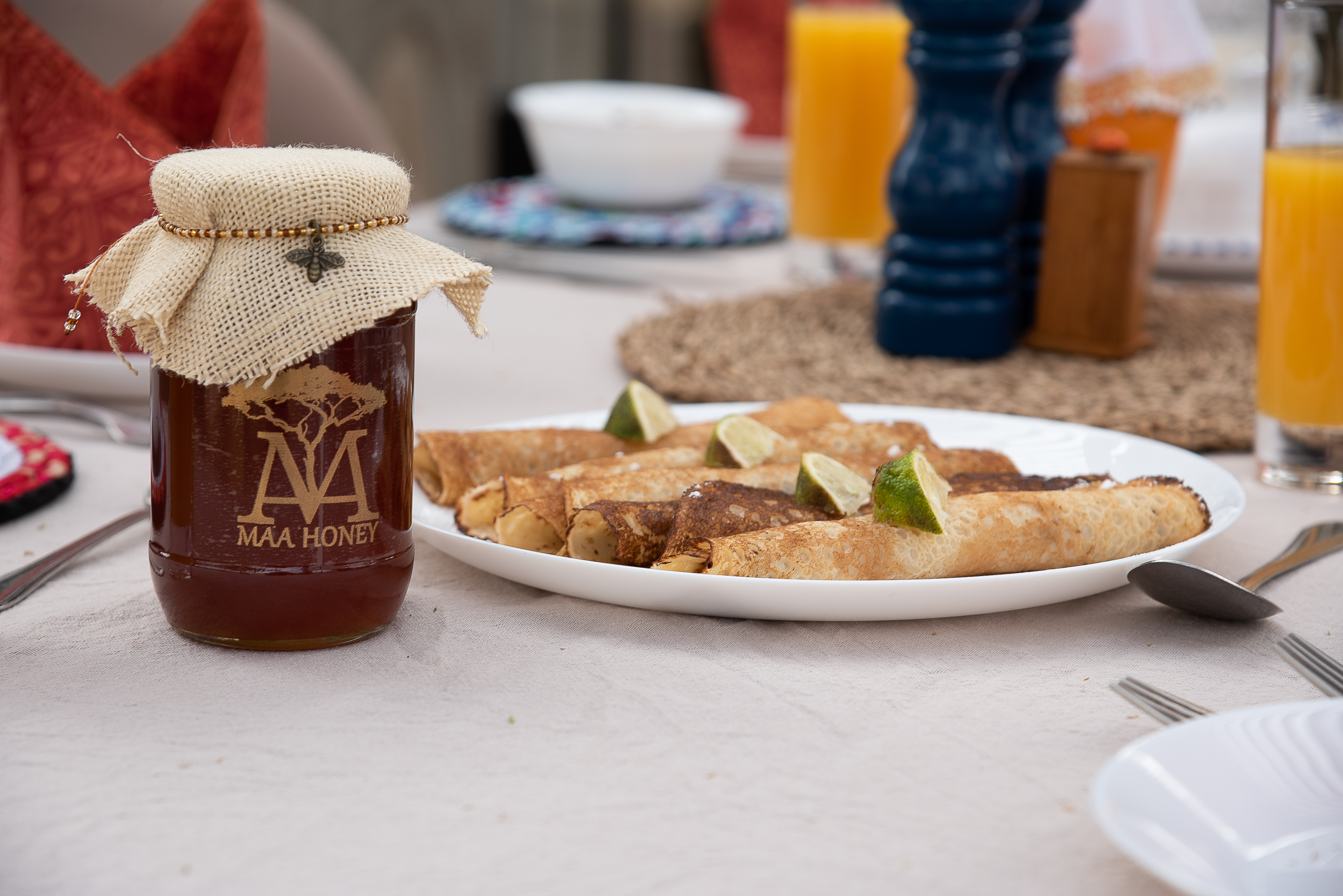 A bottle of Maa Honey sits alongside fresh pancakes on a Naboisho Camp breakfast table