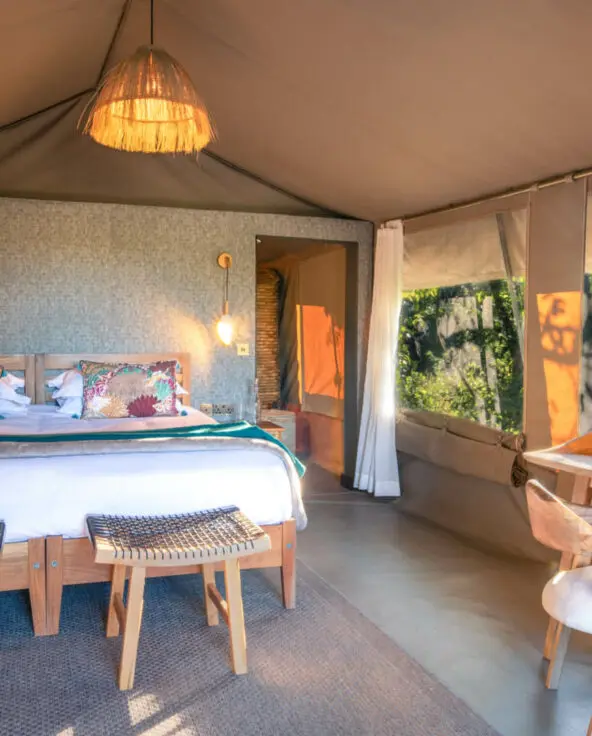 An internal view of a stylish suite at Rekero with a large bed and writing desk