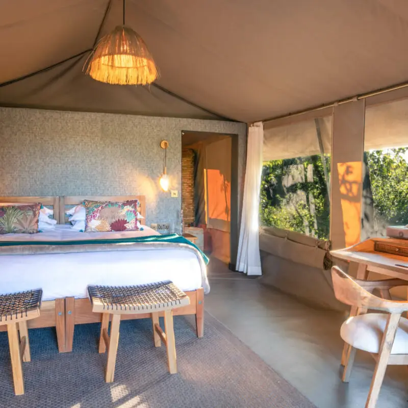 An internal view of a stylish suite at Rekero with a large bed and writing desk