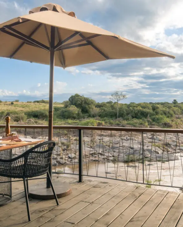 A table is set on the deck with a view of the river