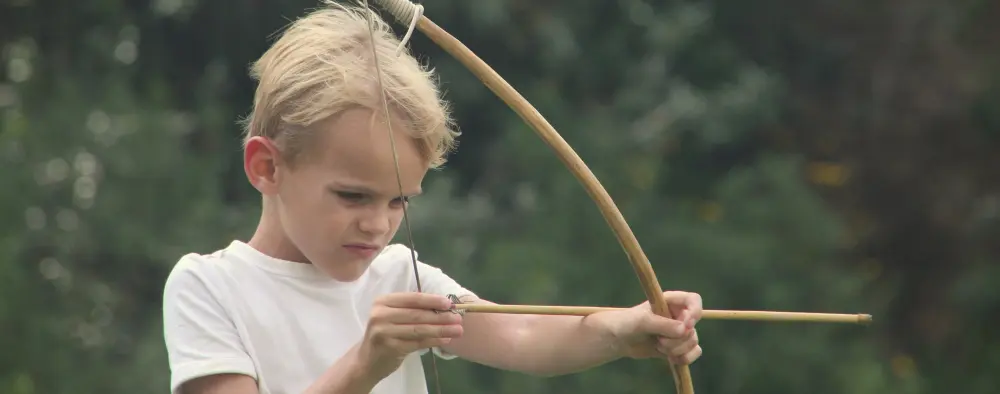 A little boy practicing with a bow and arrow