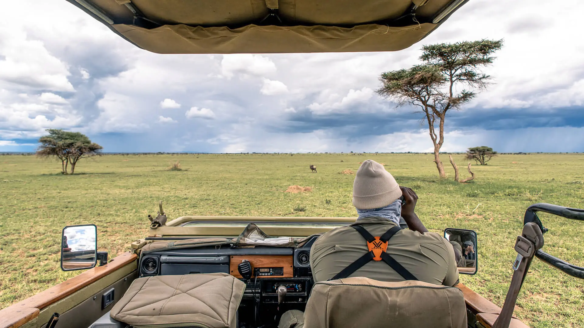 An Asilia guide looks out over the plains using binoculars