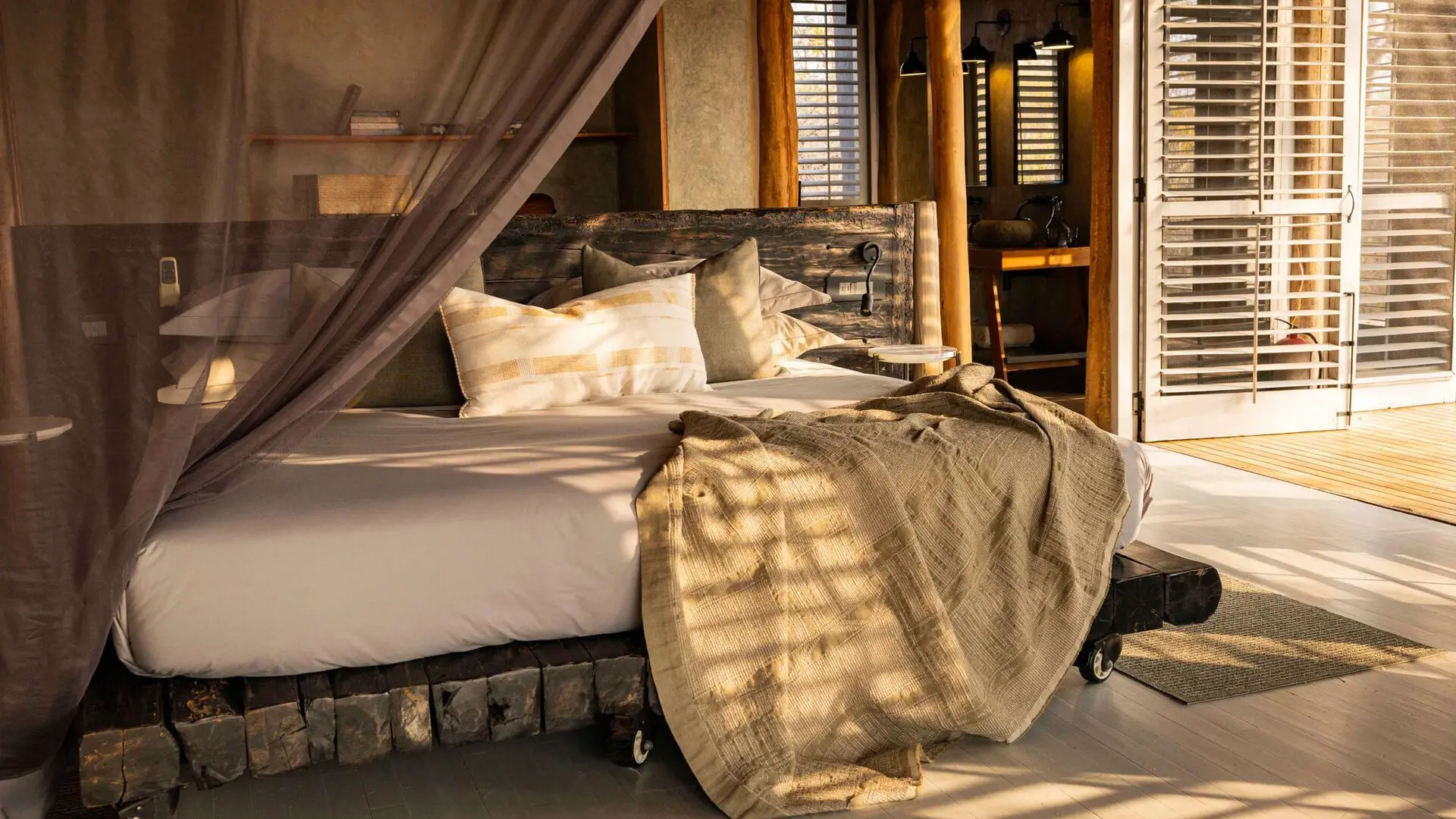 Jabali Private House, bedroom with a large bed draped in neutral linens and a mosquito net, wooden furnishings, and open shutters letting in warm natural light.