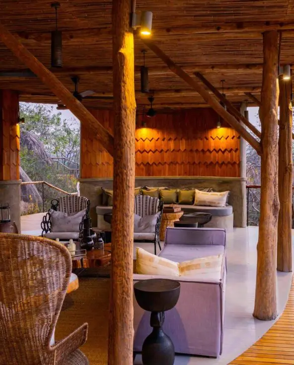 An open-air lodge lounge blending natural timber, warm lighting, and sweeping views over the wilderness
