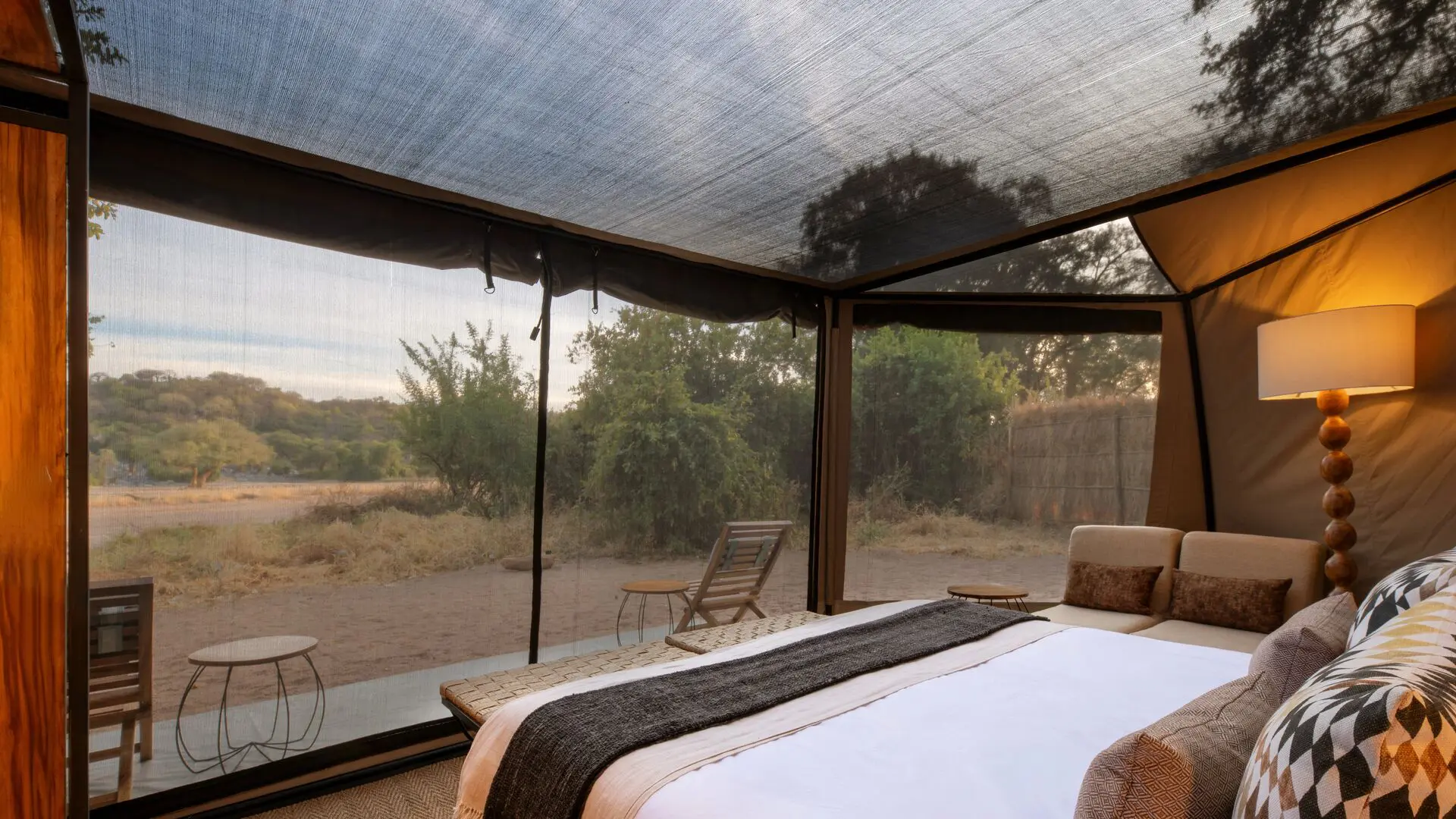 The interior of the guest tent at Kokoko Camp with large bed and mesh ceiling with views of the landscape