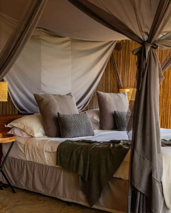 A spacious safari tent at Roho ya Selous with a canopy bed, wooden furnishings, and neutral decor