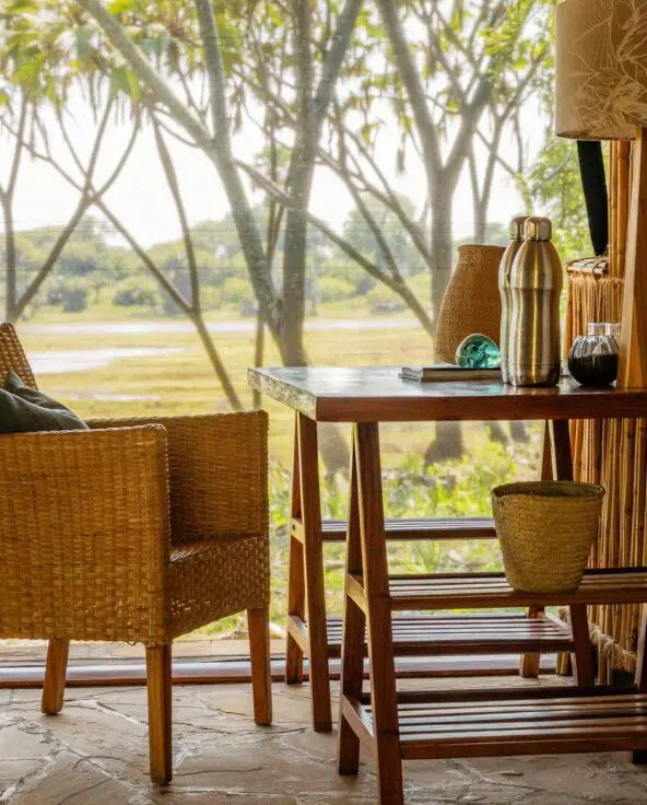 A desk and chair inside a guest tent at Roho ya Selous facing a river view through a window