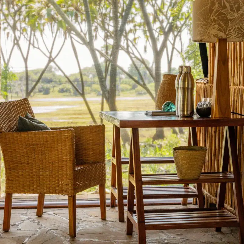 A desk and chair inside a guest tent at Roho ya Selous facing a river view through a window