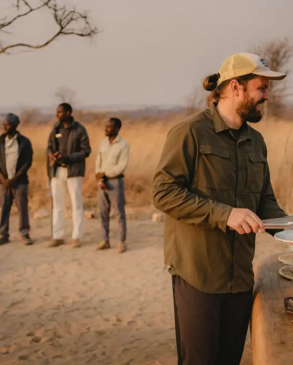 An Asilia guest is served food from a bush breakfast with staff nearby