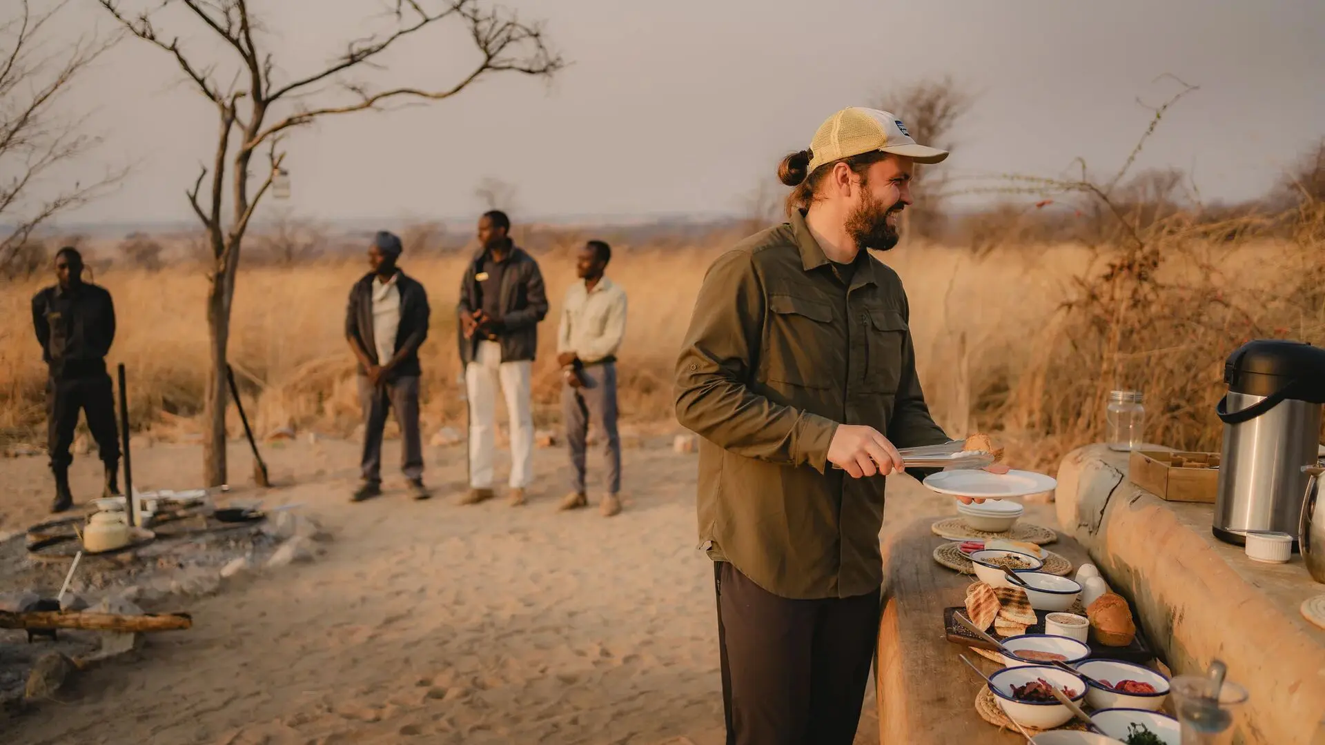 An Asilia guest is served food from a bush breakfast with staff nearby