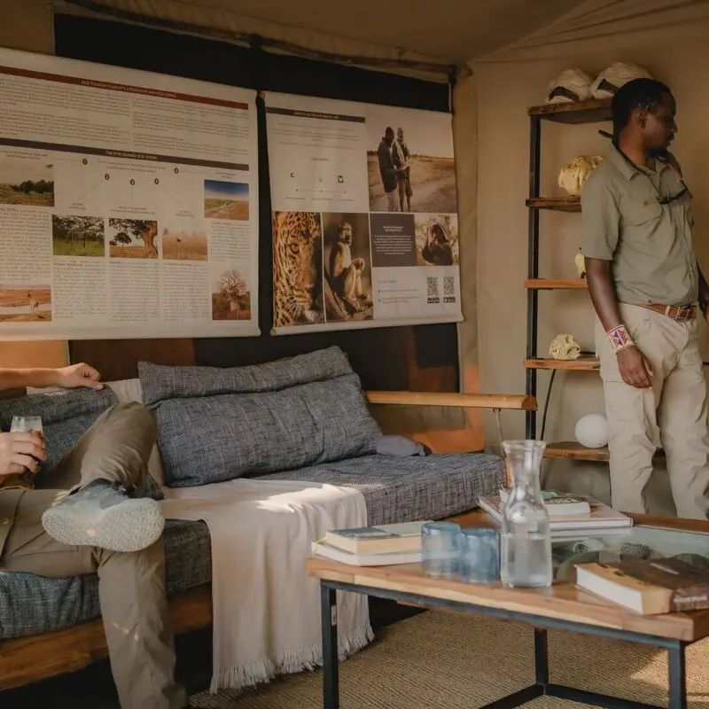 A guest seated inside a safari lounge while a guide presents information on a screen