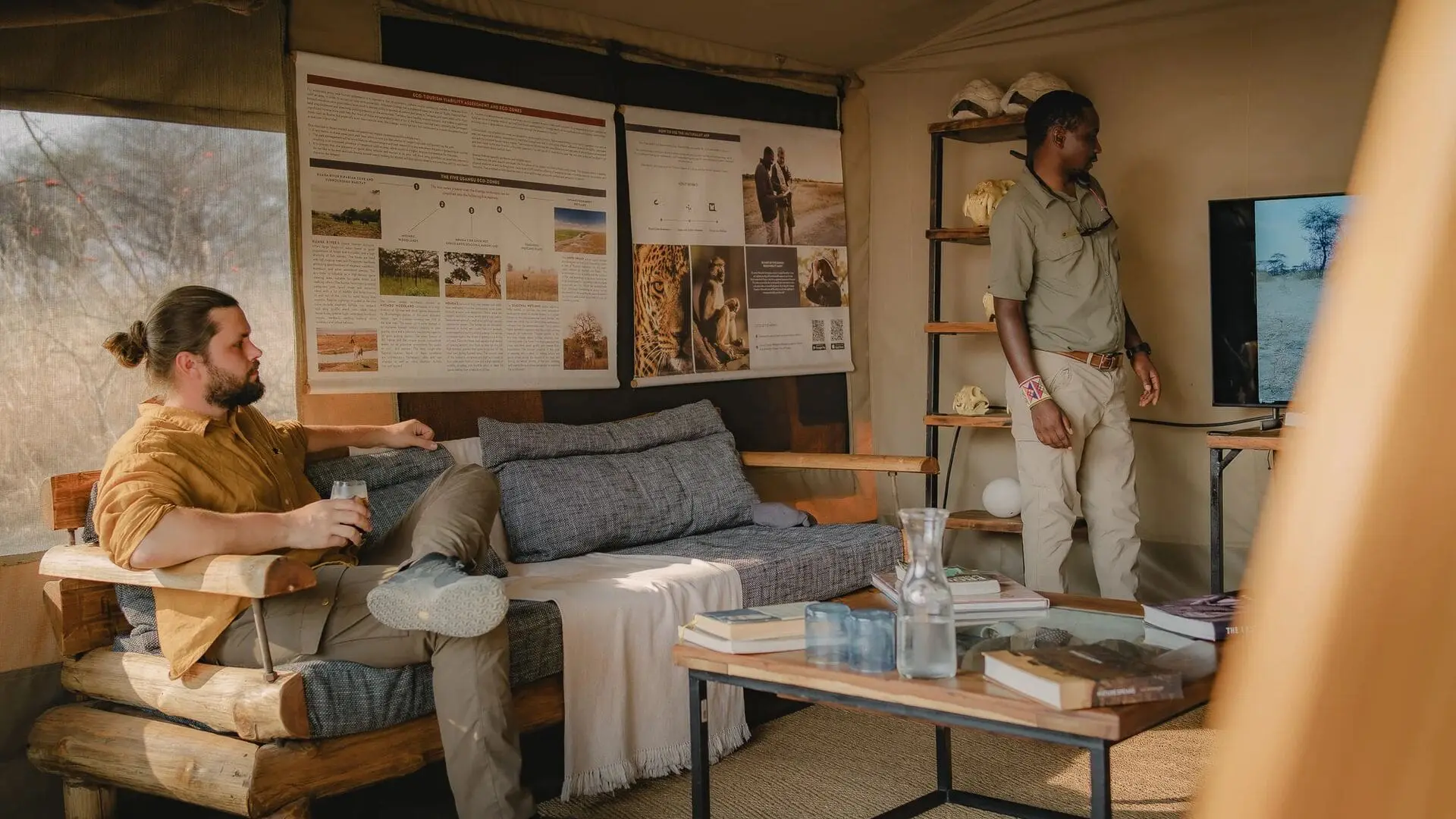 A guest seated inside a safari lounge while a guide presents information on a screen