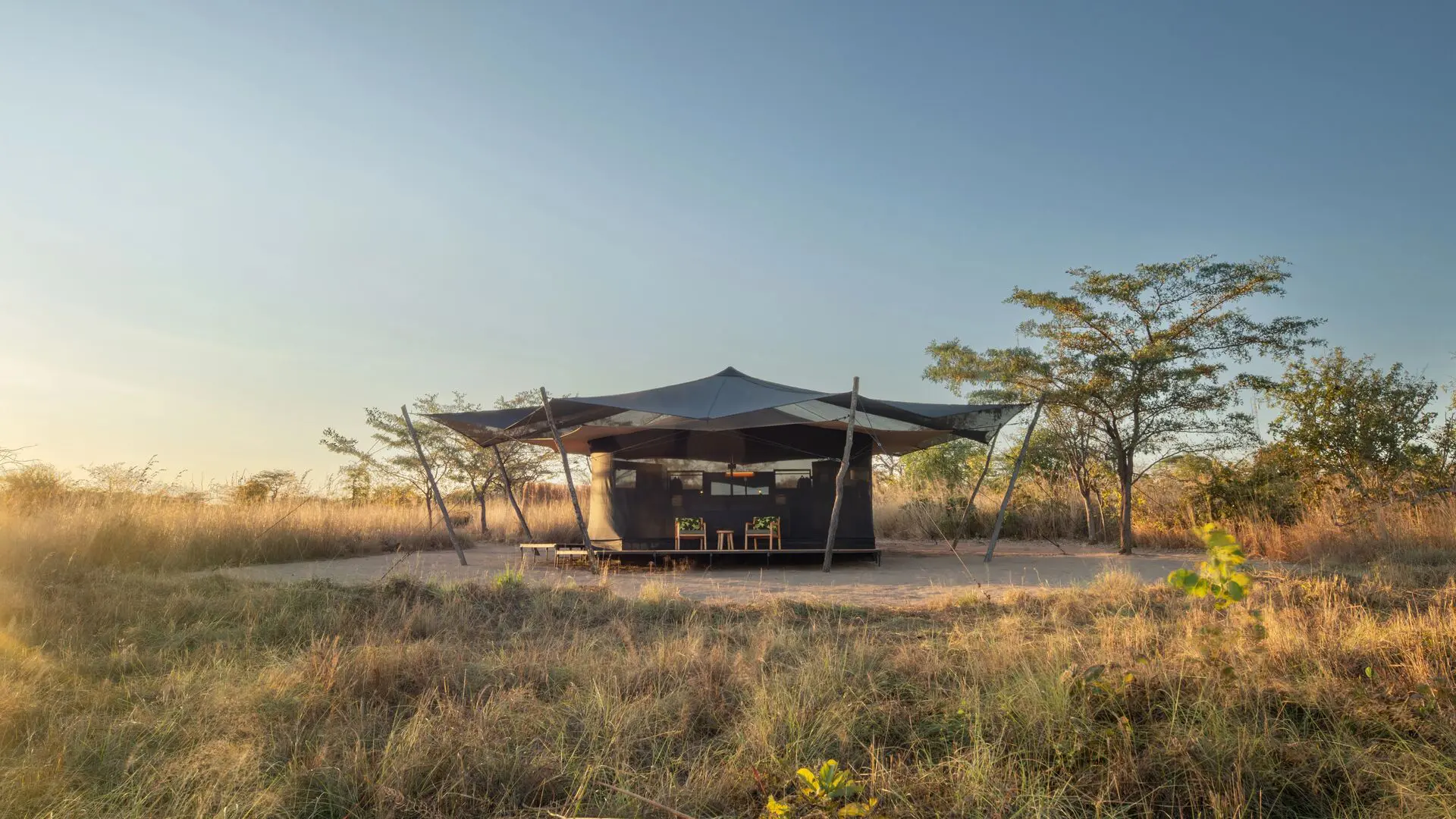 Usangu guest tent on a raised platform surrounded by dry grass and scattered trees