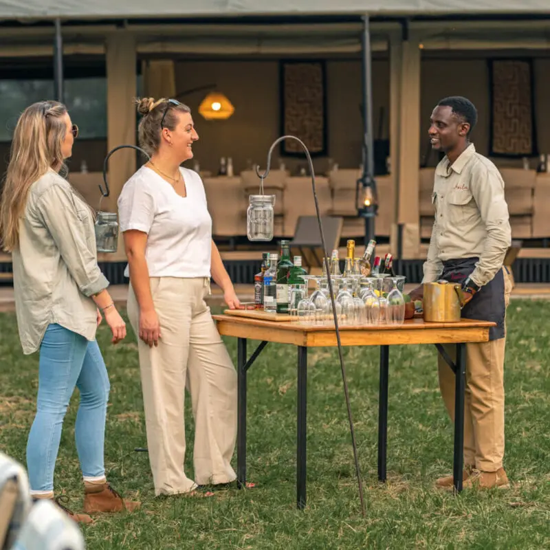 Smiling guests order a drink from an Asilia waiter