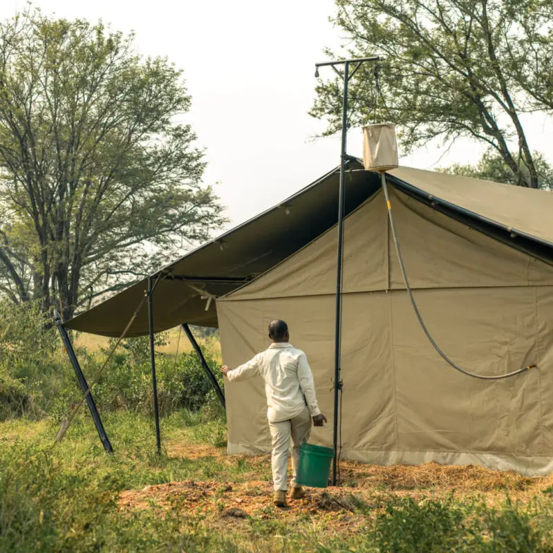 An Ubuntu staff member carries water for a guest's bucket shower