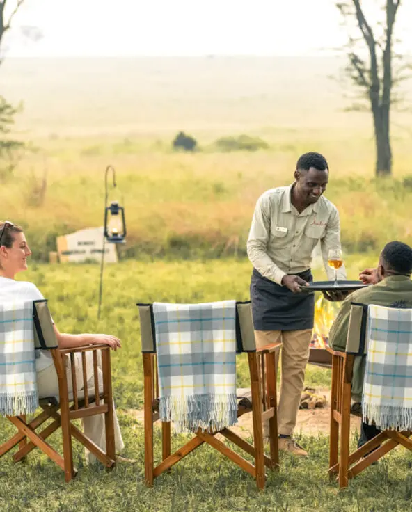 Guests receive their sundowner drinks from a smiling waiter