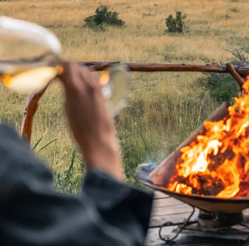 guest enjoying wine by the campfire, mara naboisho conservancy, kenya, encounter mara camp