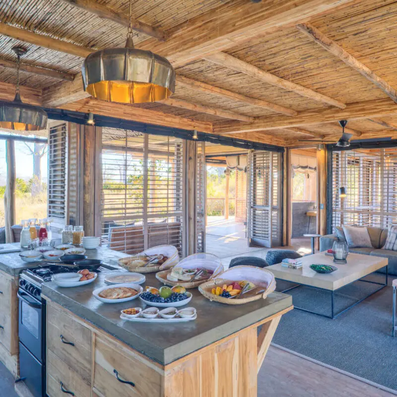 Jabali Private House, Ruaha National Park, kitchen with breakfast setup next to the lounge area and leading on to the deck with shutter doors open