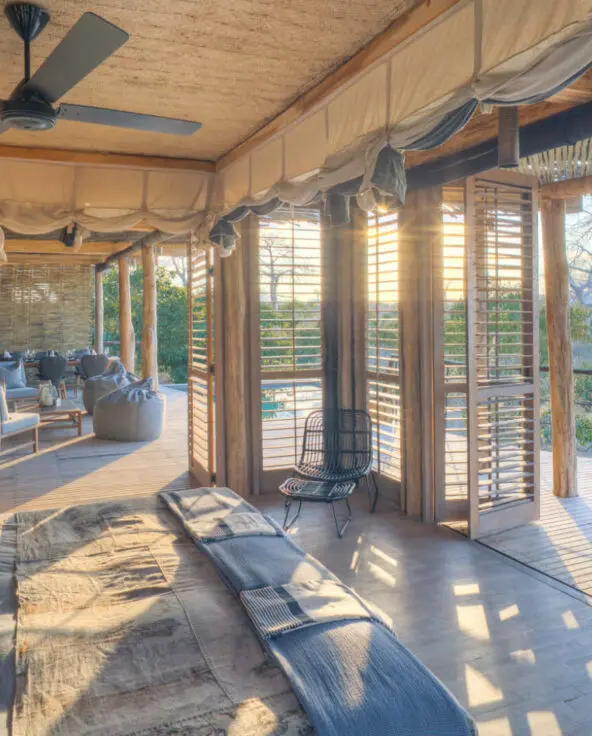 Jabali Private House, Ruaha National Park, double room interior with double bed with pillows and throw blanket, shutters open to the deck and main area, chair in the corner