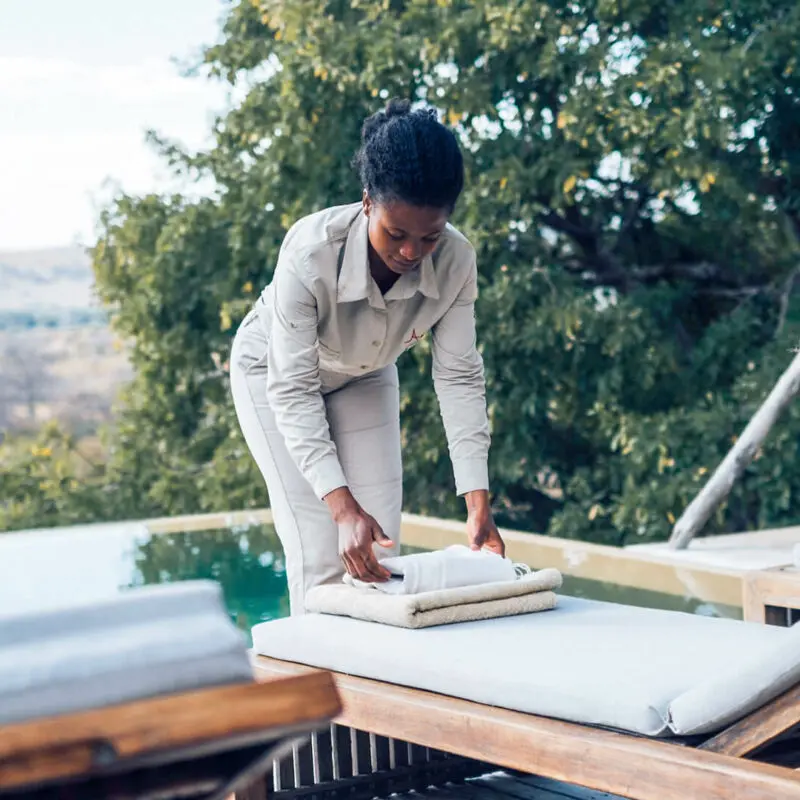 Jabali Ridge, Ruaha National Park, camp staff placing folded towels on the lounger by the pool