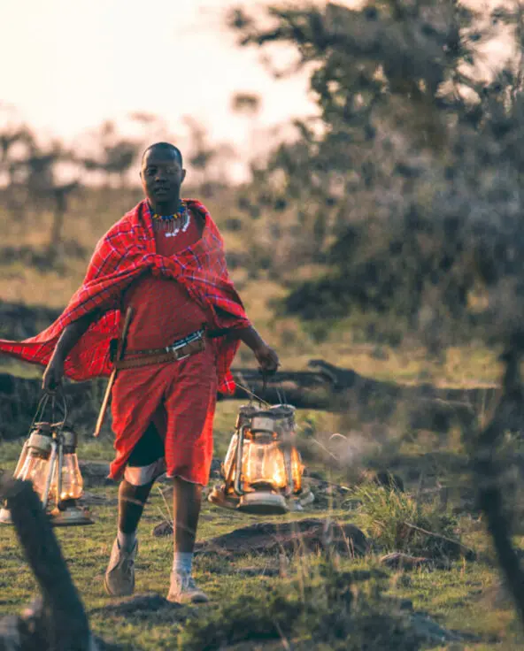 Masai guide walking with lanterns at sunset, naboisho camp, mara naboisho conservancy, kenya