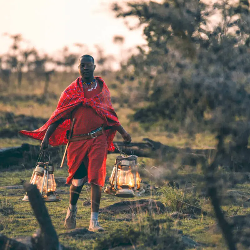 Masai guide walking with lanterns at sunset, naboisho camp, mara naboisho conservancy, kenya