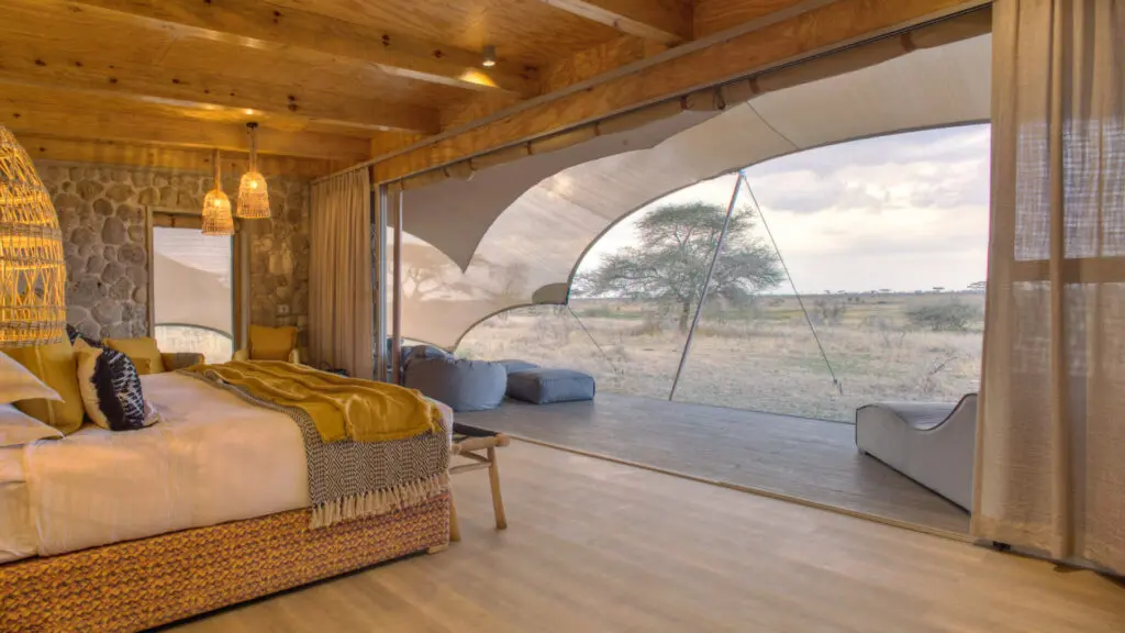 Namiri Plains, Serengeti National Park, guest tent interior, hanging lights, couches, bed made, curtains drawn and doors open