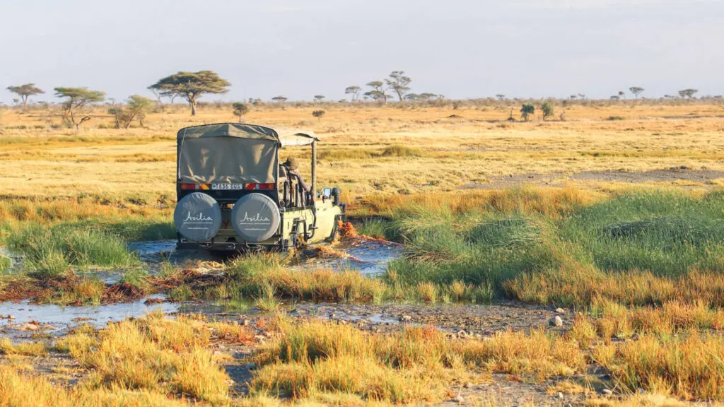 Namiri Plains Retreat, Serengeti National Park, guests on game drive through wet terrain