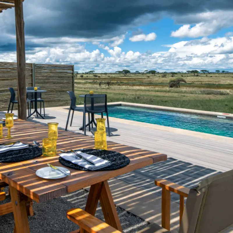 Namiri Plains Retreat, Serengeti National Park, lunch setup at the pool, table and chairs on the deck, placemats and shanga glasses on the table