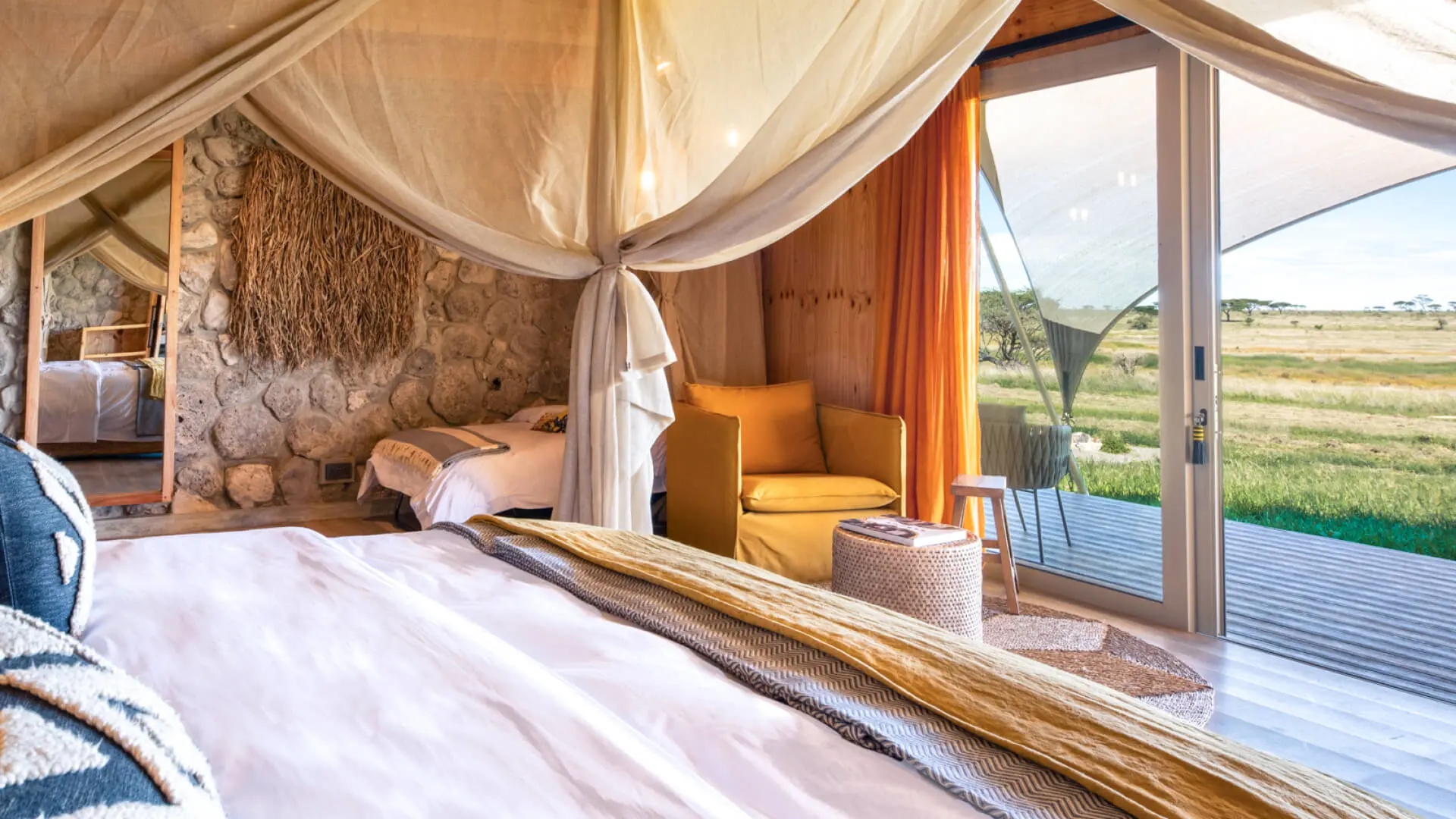 Namiri Plains Retreat, Serengeti National Park, guest room interior bed made, couch and children's bed, doors open