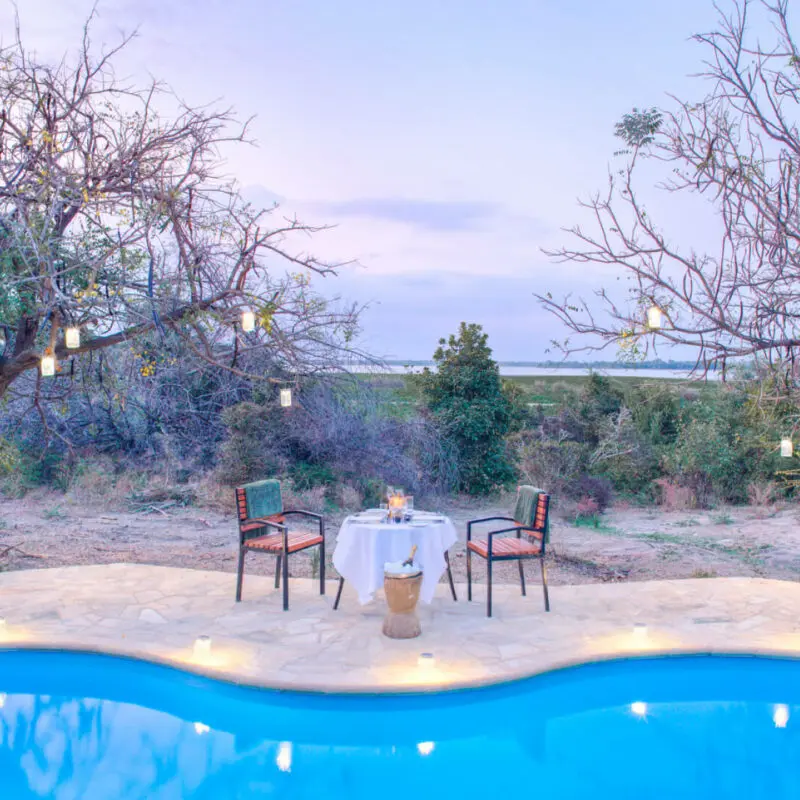 Roho ya Selous Camp, Nyerere National Park, Dining setup by the pool, lanterns hanging in the trees