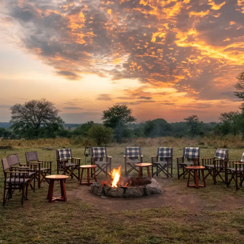 Sayari Camp, Northern Serengeti, chairs around firepit at dusk, sun setting