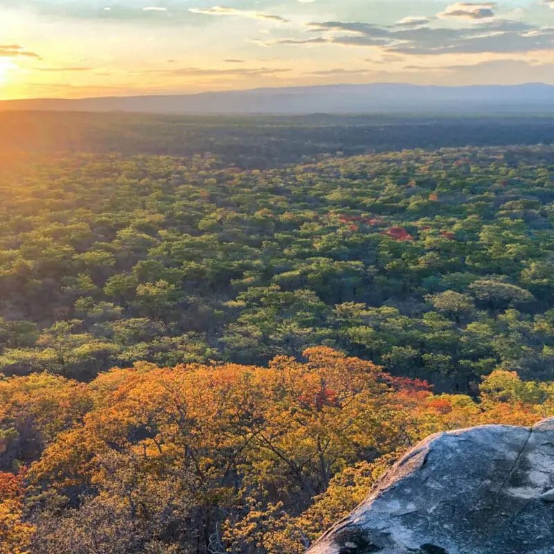 Usangu Expedition Camp, Ruaha National Park, guest standing on a rock watching the sunset over the park