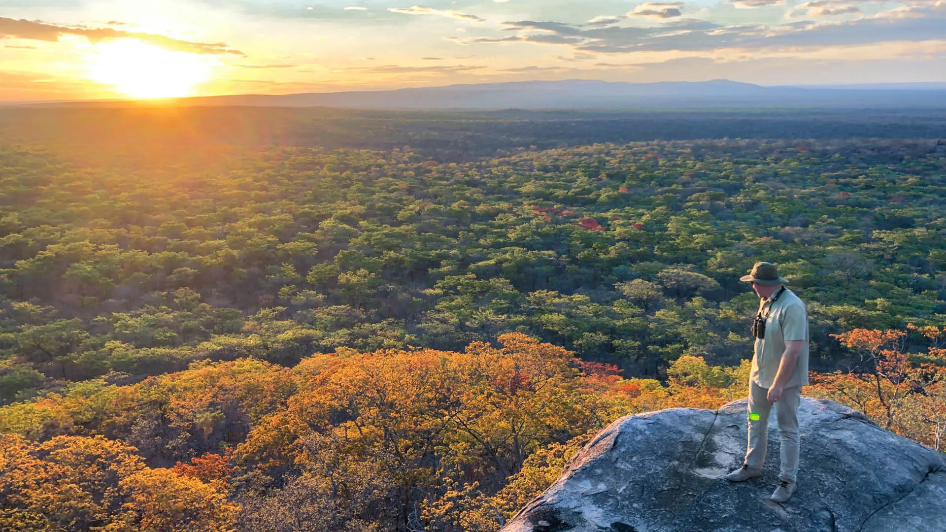 Usangu Expedition Camp, Ruaha National Park, guest standing on a rock watching the sunset over the park