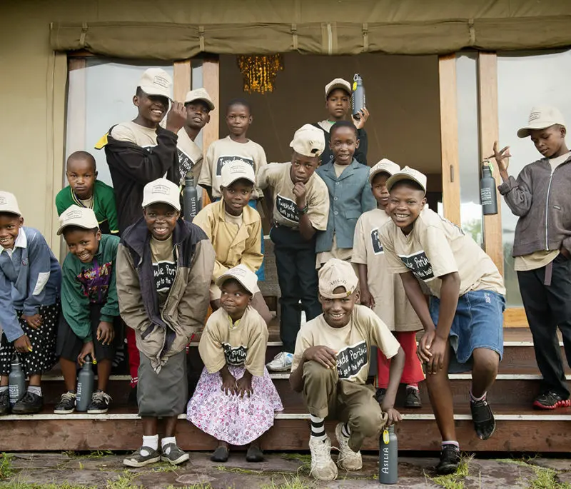 A group of young children wearing Porini t-shirts stand for a photo