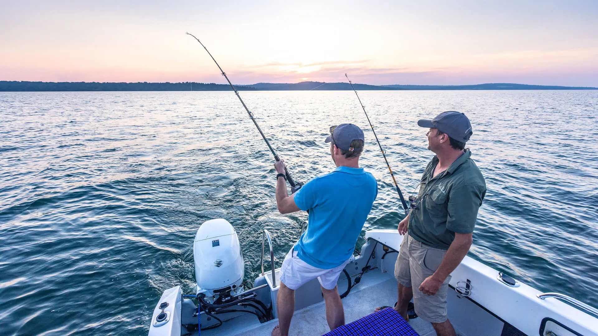 Two men fishing off the back of the boat on Lake Victoria, Tanzania - Asilia Africa
