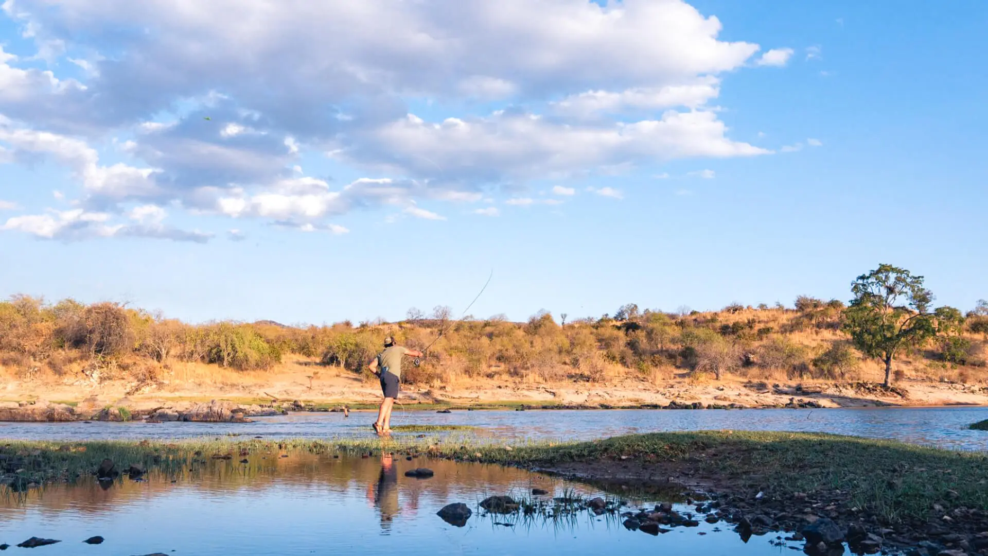 A guest casts their line onto the water on a fishing safari