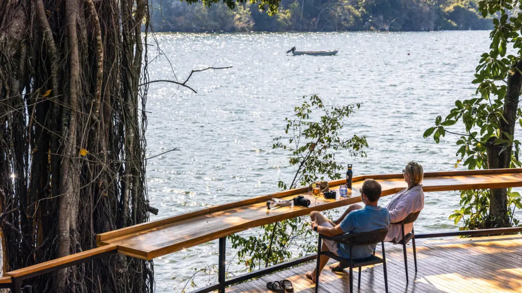 A couple relax on the deck overlooking Lake Victoria from Rubondo Island camp in Tanzania - Asilia Africa