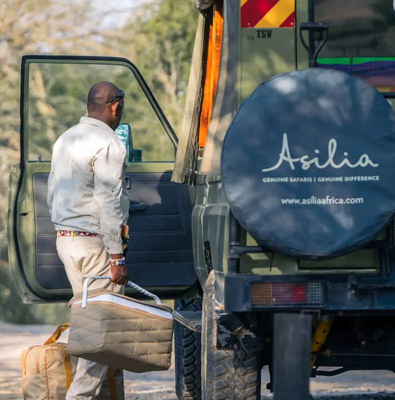 Male staff putting a picnic into a safari vehicle at Ol Pejeta Bush Camp in Kenya