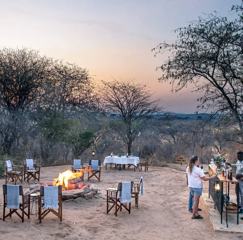 Guests enjoying sundowners around the campfire, olivers camp, Tarangire National Park, Tanzania
