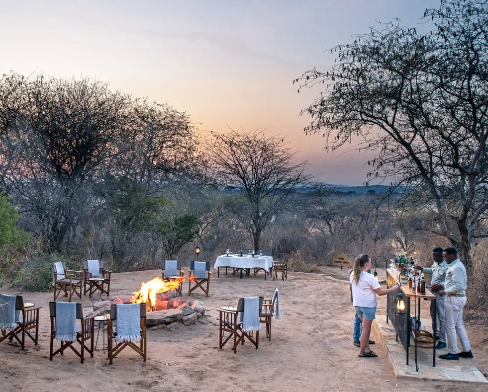 Guests enjoying sundowners around the campfire, olivers camp, Tarangire National Park, Tanzania