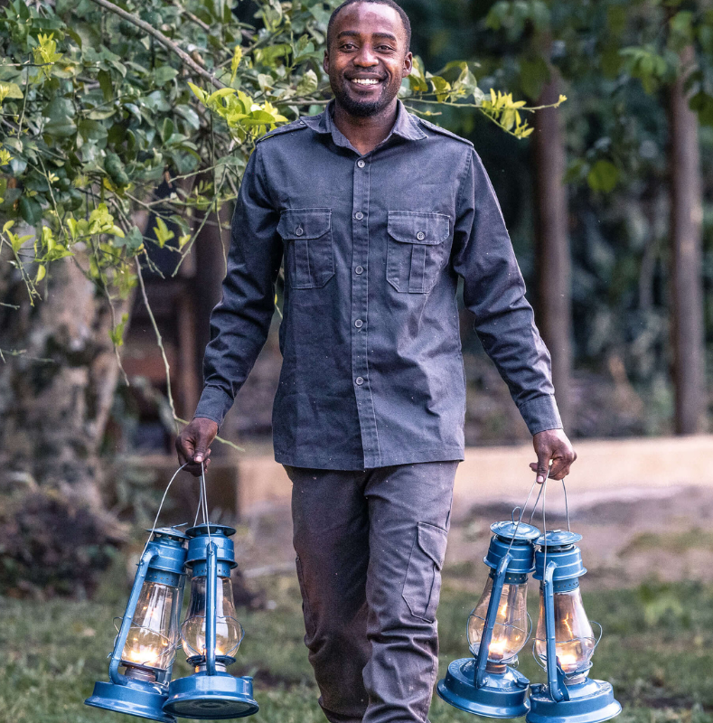 male staff member smiling, carrying night lamps, rubondo island, tanzania, asilia africa