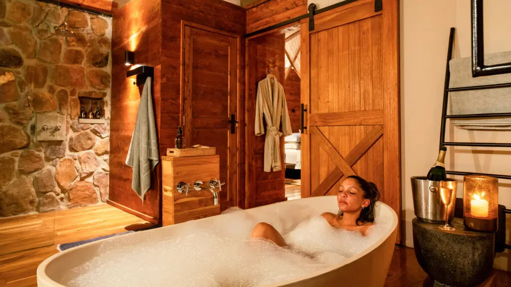 lady in a bubble bath with a glass of champagne at asilia africa's sayari retreat in tanzania east africa
