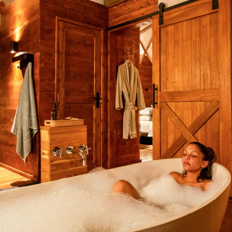 lady in a bubble bath with a glass of champagne at asilia africa's sayari retreat in tanzania east africa