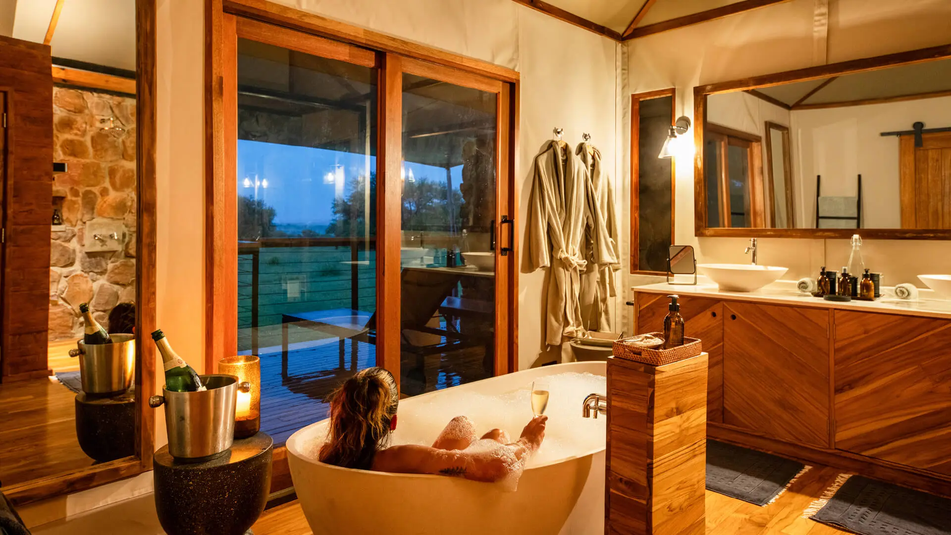 lady in a bubble bath with a glass of champagne at asilia africa's sayari retreat in tanzania east africa