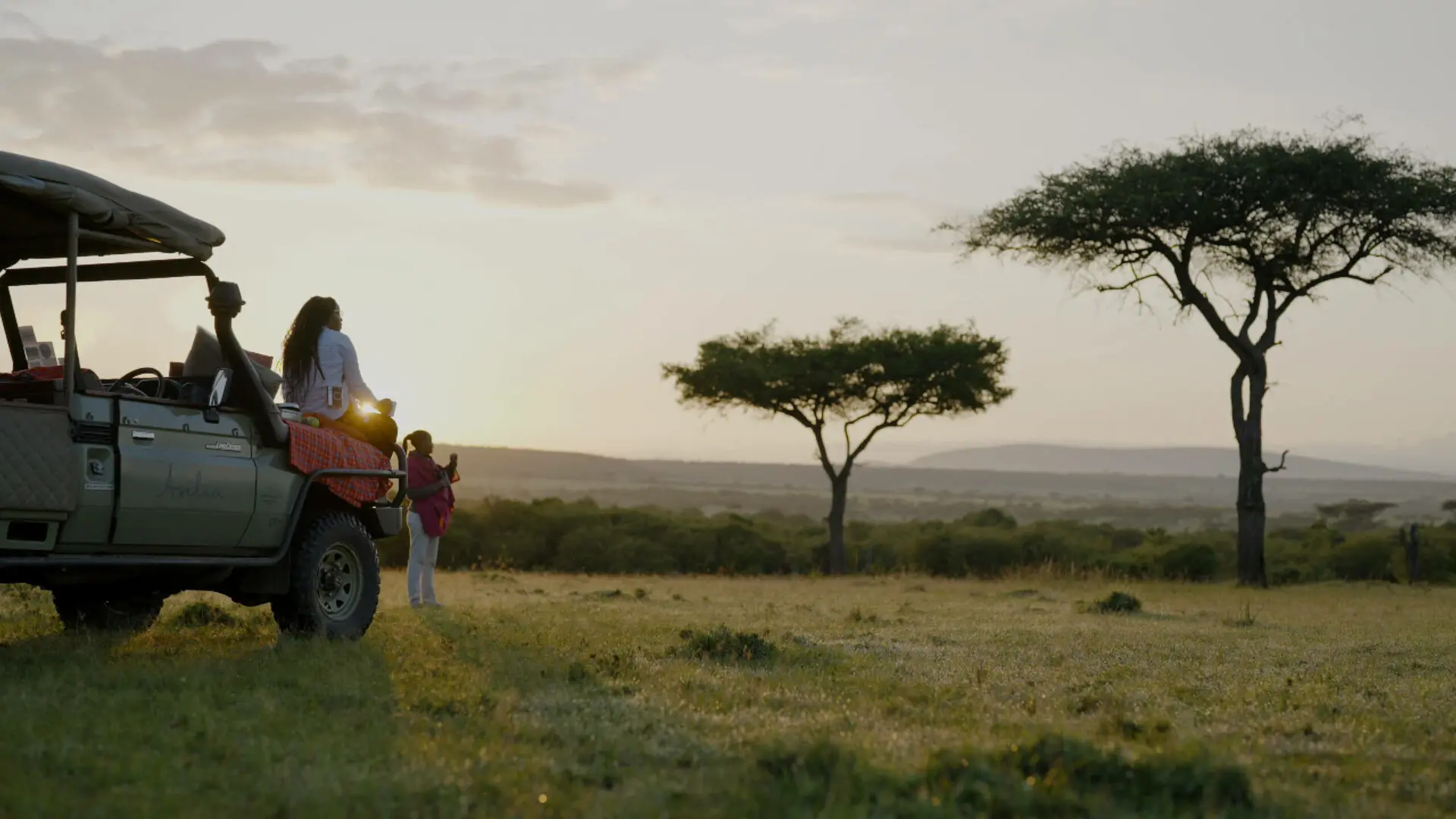 Female guest sat on a safari vehicle watching the sunset in east africa